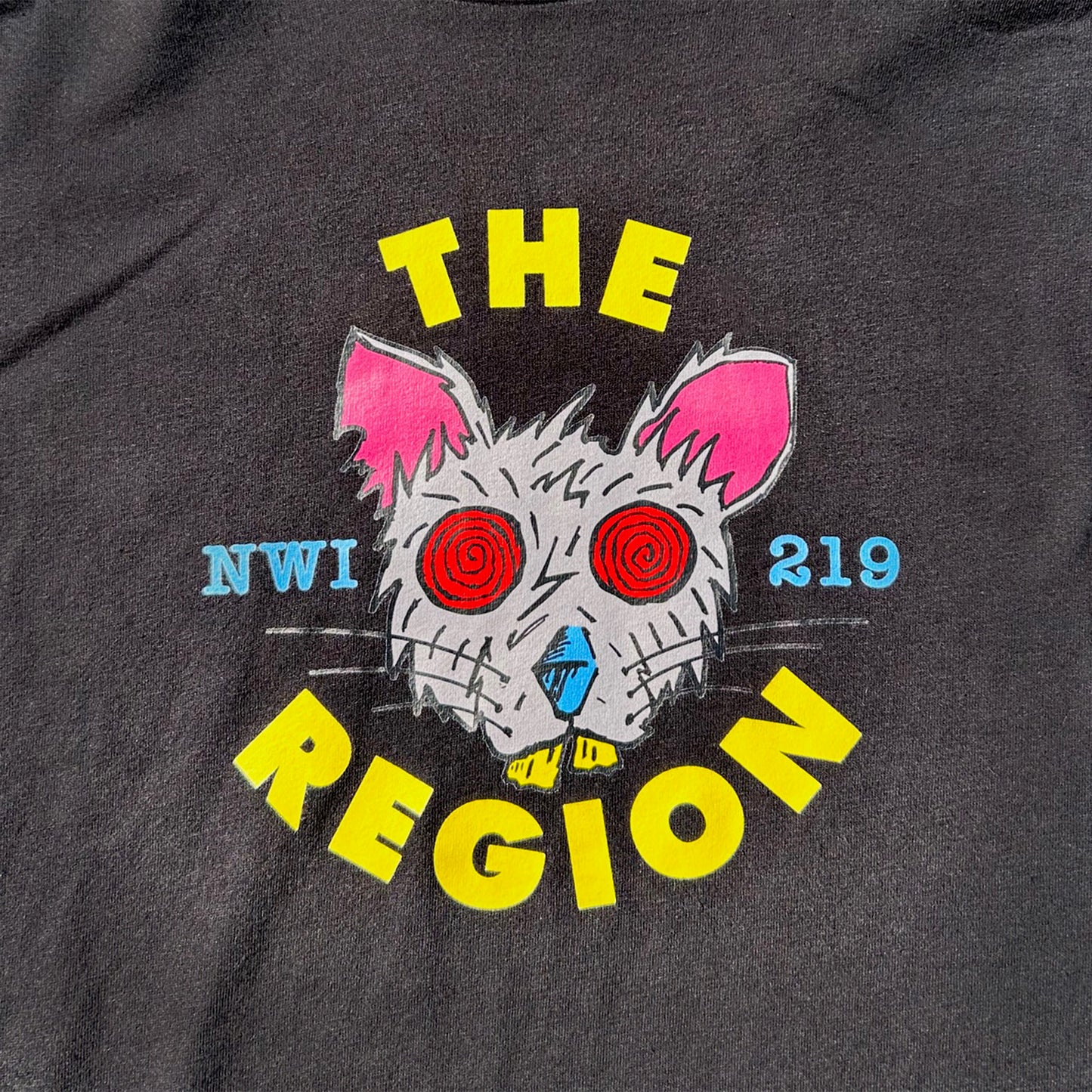 Black t-shirt with a graphic of a Region Rat's face and text 'THE REGION NWI 219' on a dark background