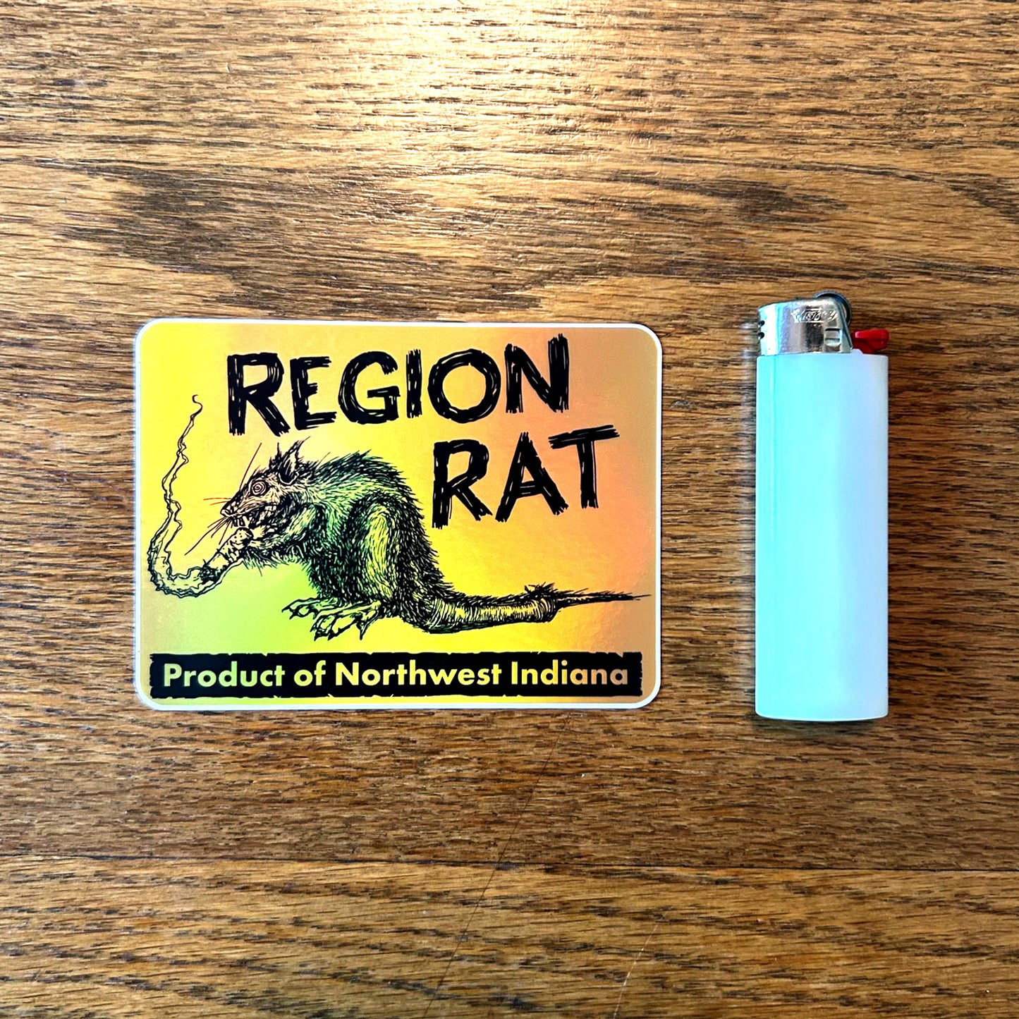 Sticker with Region Rat art and a lighter on a wooden surface