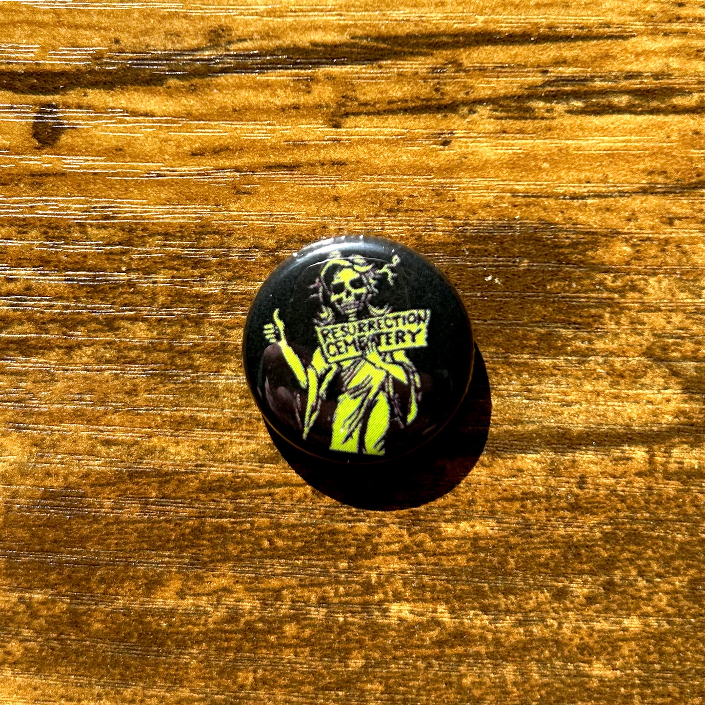Resurrection Mary pin round black pin with green ghost art on wood table