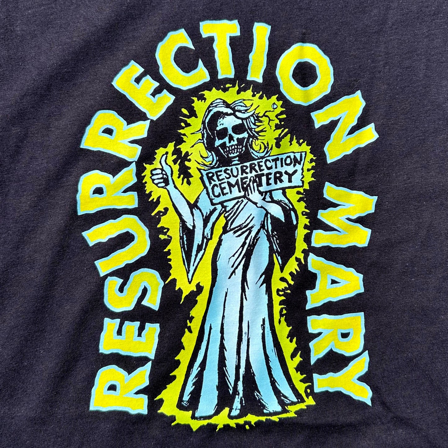 T-shirt with 'Resurrection Mary' graphic design featuring a skeleton ghost holding a sign.