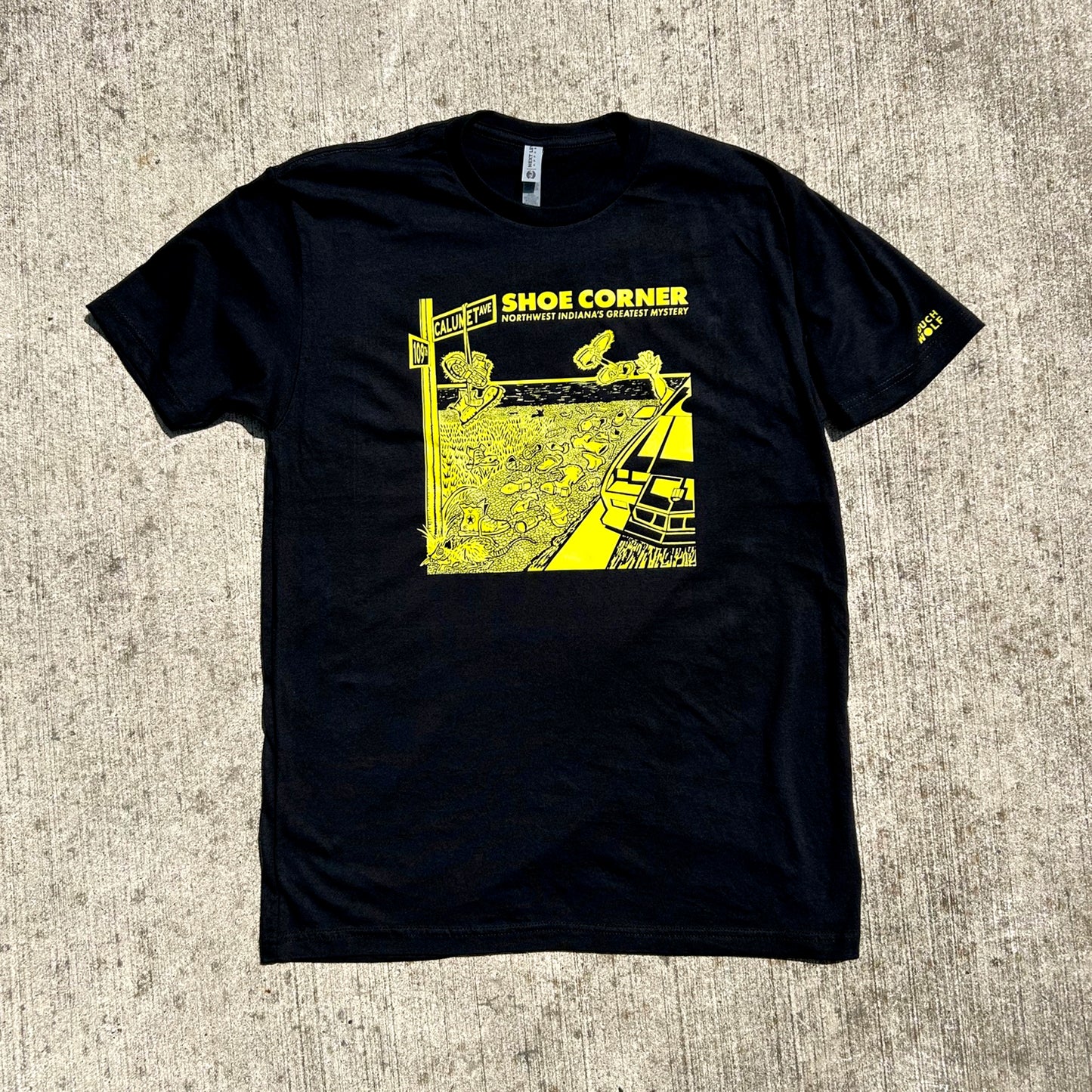 Black t-shirt with yellow graphic design on a textured surface