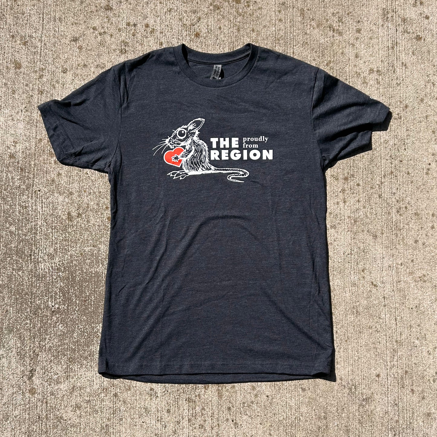 Region Rat Indiana shirts says proudly from the region with white ink drawing of rat holding red heart on gray shirt on tan concrete background
