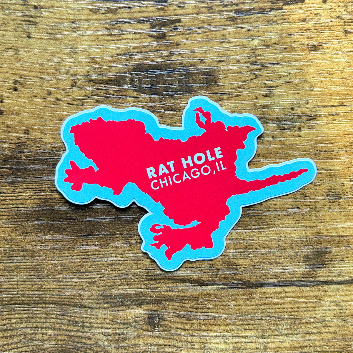 Chicago Rat Hole Sticker red and blue sticker in the shape of rat hole says rat hole chicago, il in white letters shown on wood surface
