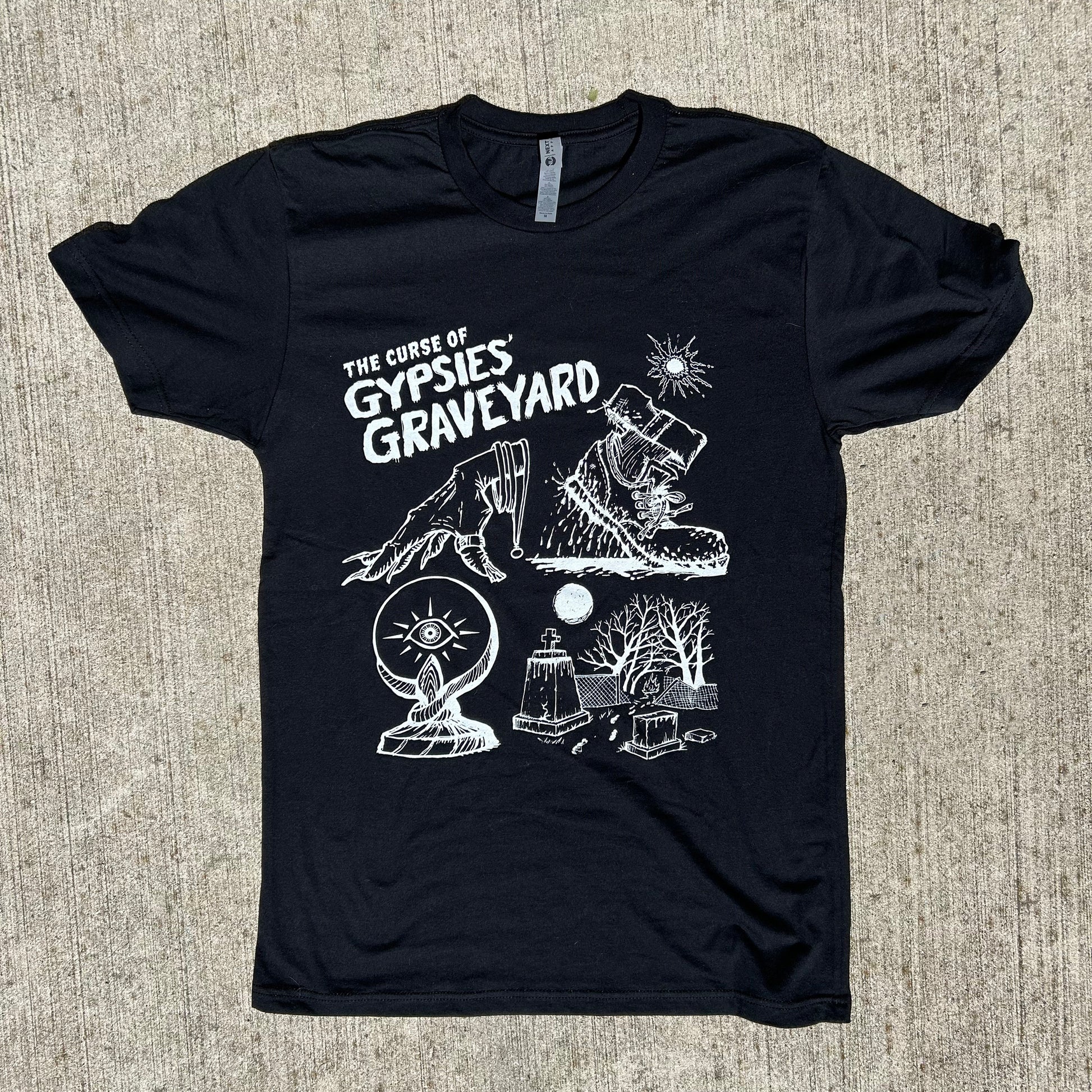 Gypsies Graveyard Indiana paranormal ghost shirt black shirt features white ink art of hand over crystal ball, blood soaked shoe and graveyard with destroyed fence says "the curse of gypsies graveyard", short sleeve crew neck shirt on concrete background
