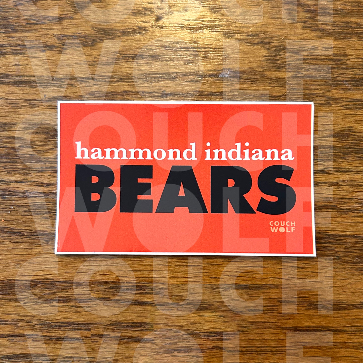 A rectangular orange sticker with a white border featuring the text 'hammond indiana BEARS' in navy blue and black, placed on a brown wood-grain surface. A faint Couch Wolf watermark is visible across the image.