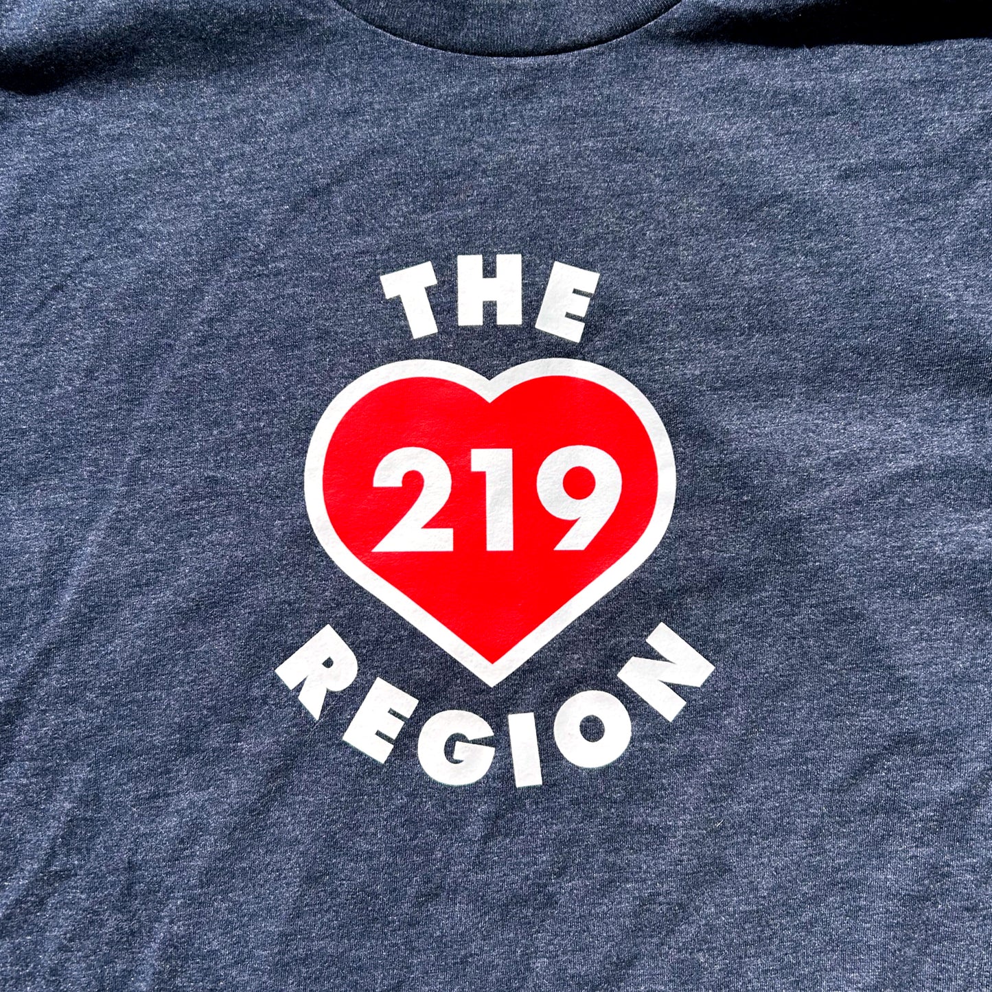 Navy blue t-shirt with a red heart and white text 'THE 219 REGION' on a dark background