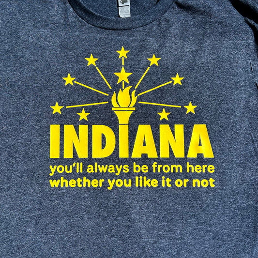 Indiana Flag T-shirt navy blue shirt with yellow bold letters that say "indiana you'll always be from here whether you like it or not" a close up of shirt chest