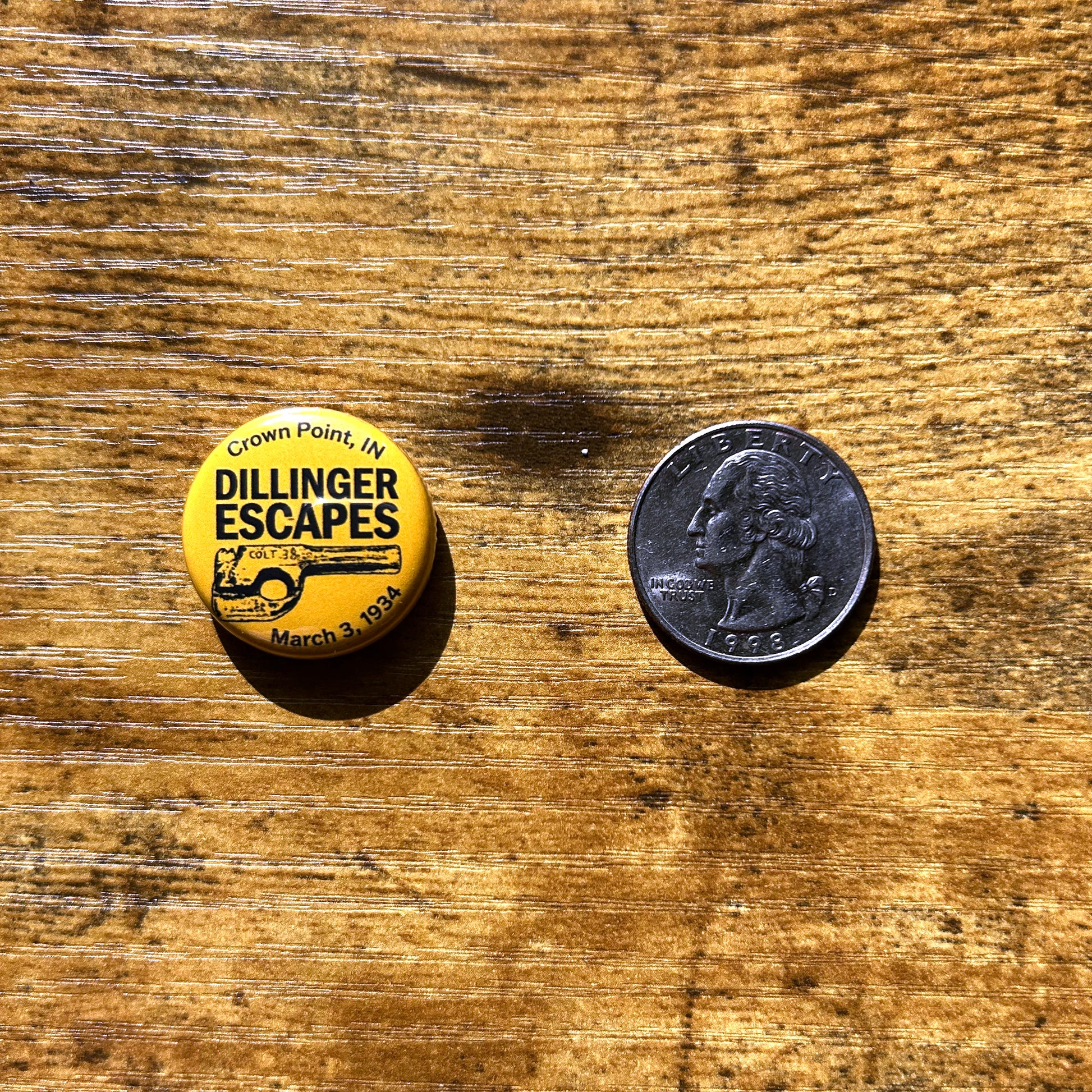 Dillinger escapes pin yellow pin next to quarter on wood surface
