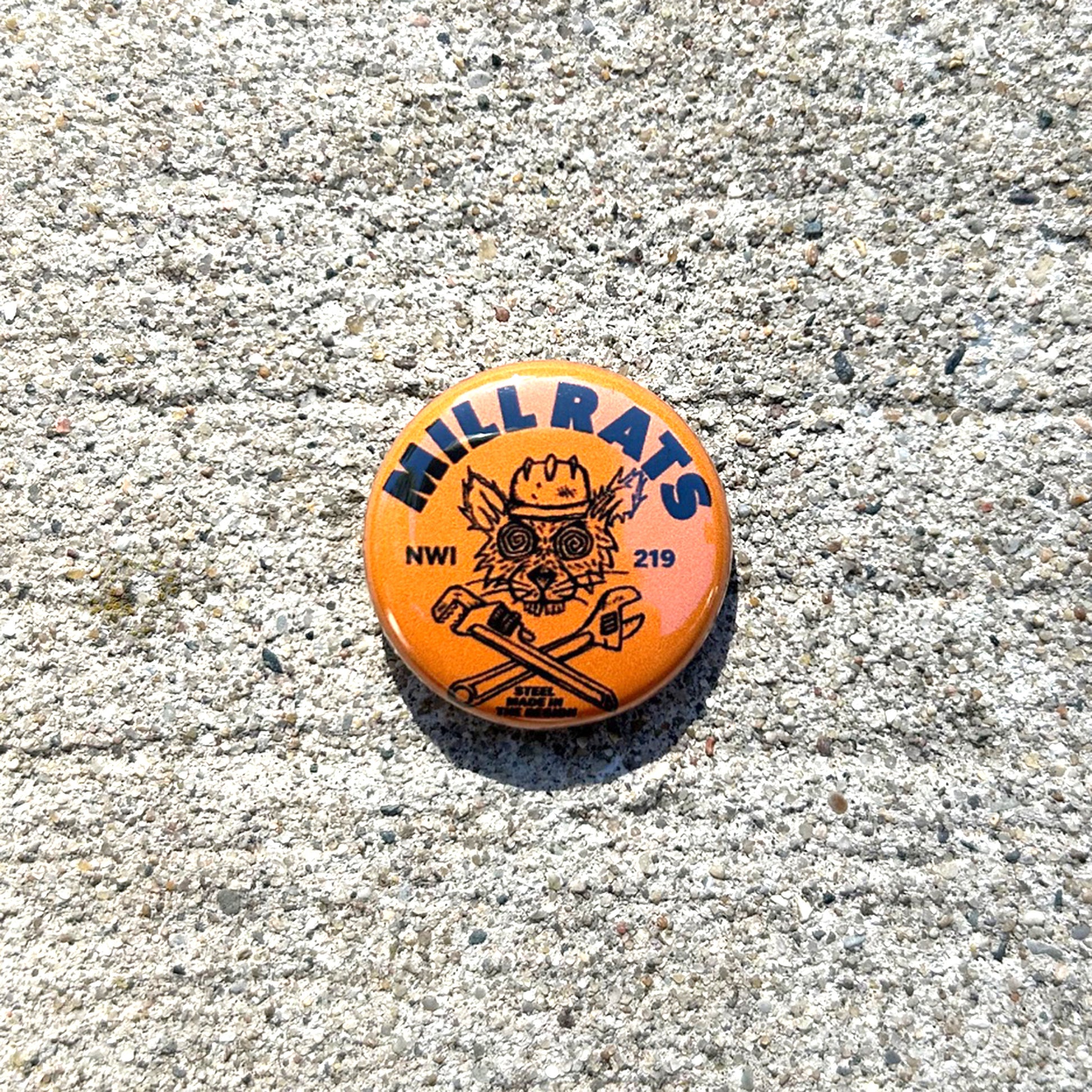 Round button with 'Mill Rats NWI 219' text and graphics on a concrete surface