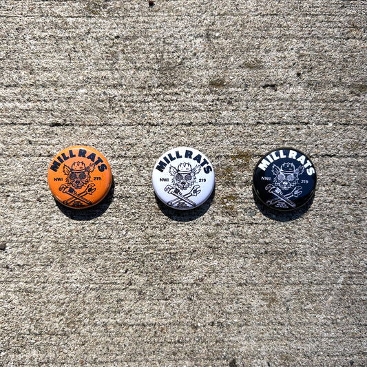 Three buttons with 'Mill Rats' logo on a concrete surface