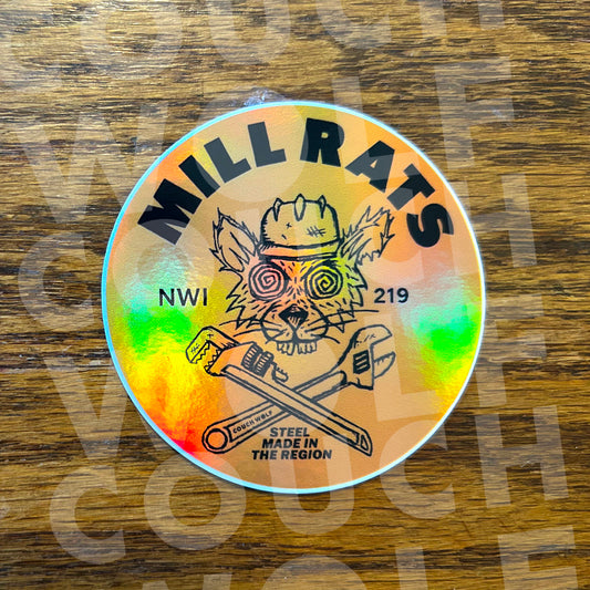 A round holographic sticker featuring a cartoon rat wearing a hard hat with the text 'MILL RATS' and 'STEEL MADE IN THE REGION', placed on a wooden surface.