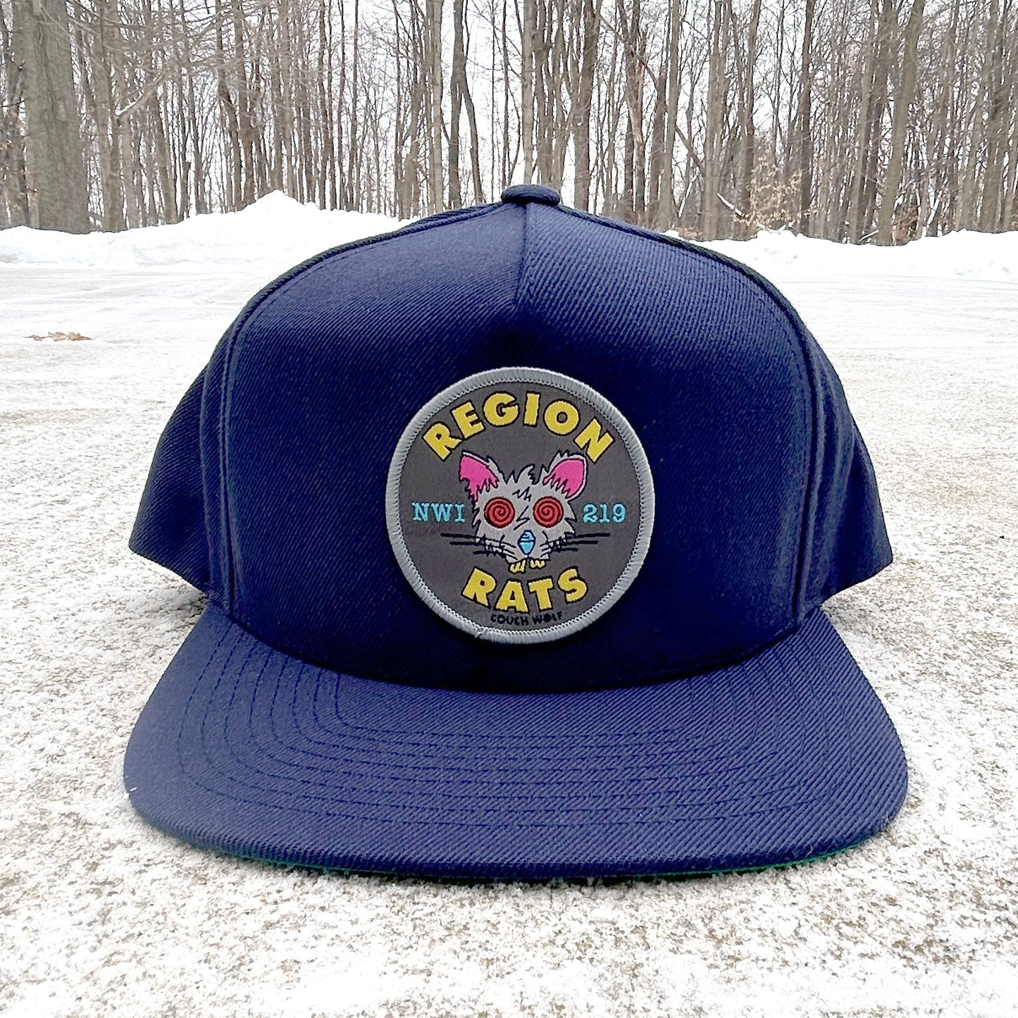 Navy blue hat with a circular Region Rat  patch featuring graphics and text on a snowy ground.