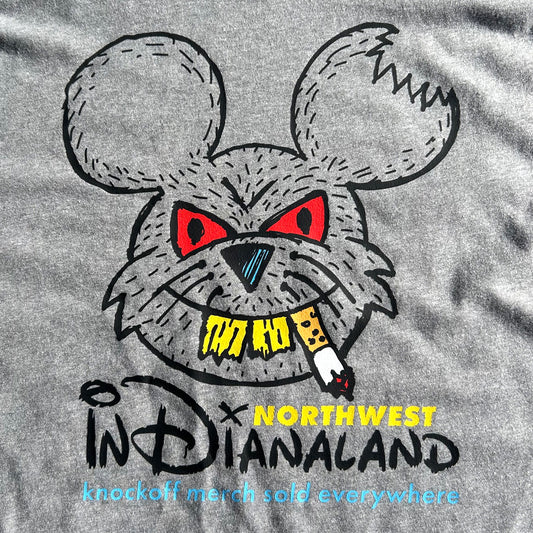 Close-up of a heather gray T-shirt featuring a stylized cartoon rat head with red eyes, a black nose, yellow text reading 'NORTHWEST INDIANALAND', and a small smoking cigarette graphic.
