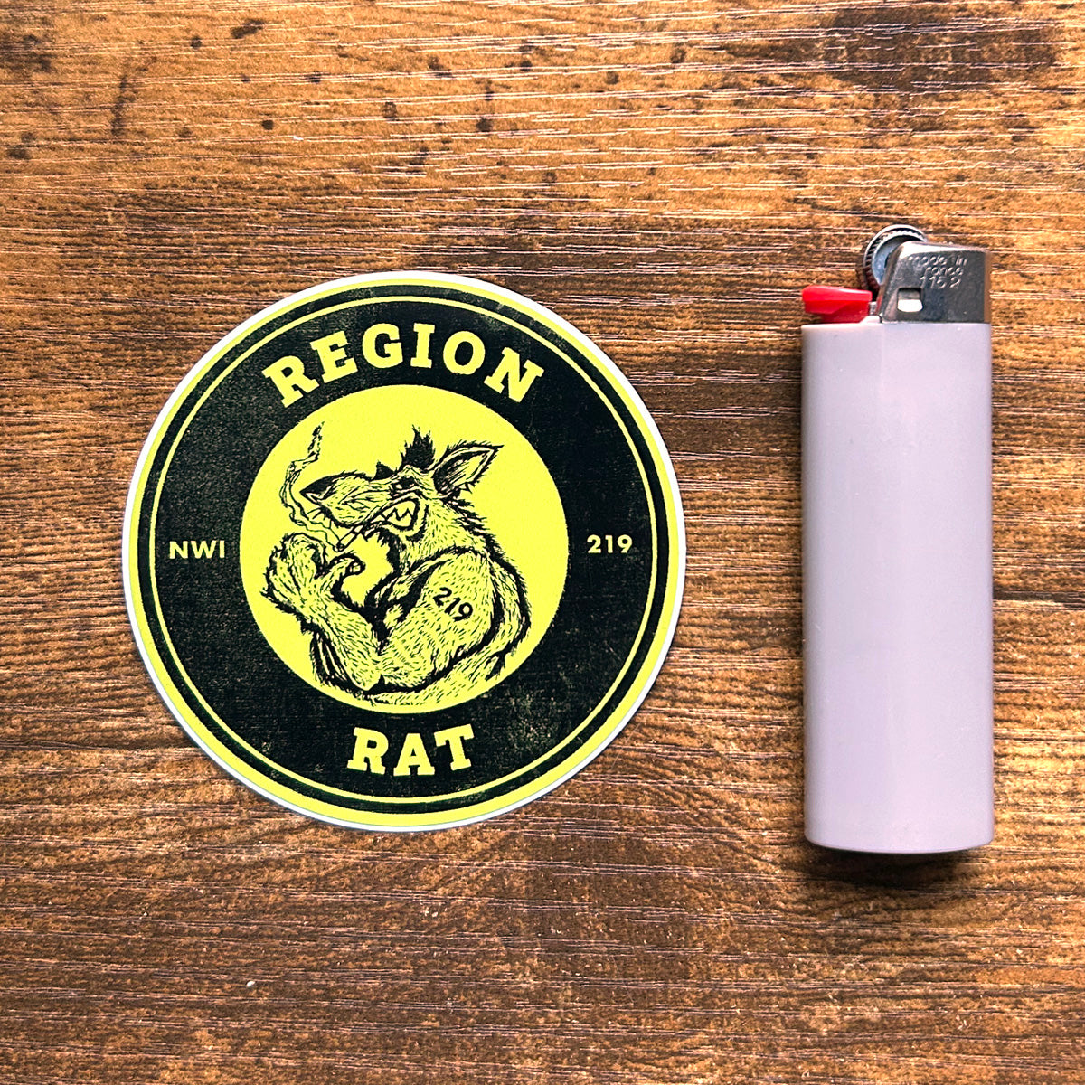 region rat sticker northwest indiana Region Rat sticker the region indiana sticker says "region rat  nwi 219" features flexing buff rat artwork  circle sticker on wood floor background next to gray pic lighter region rat upper body image on sticker