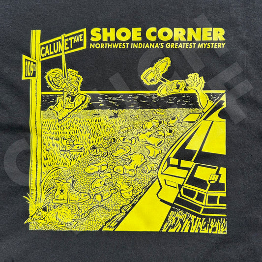 Black t-shirt with yellow graphic design of a shoe corner and text on a dark background
