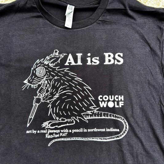 Black t-shirt with white graphic and text 'AI is BS Couch Wolf art by a real person with a pencil' on a plain background